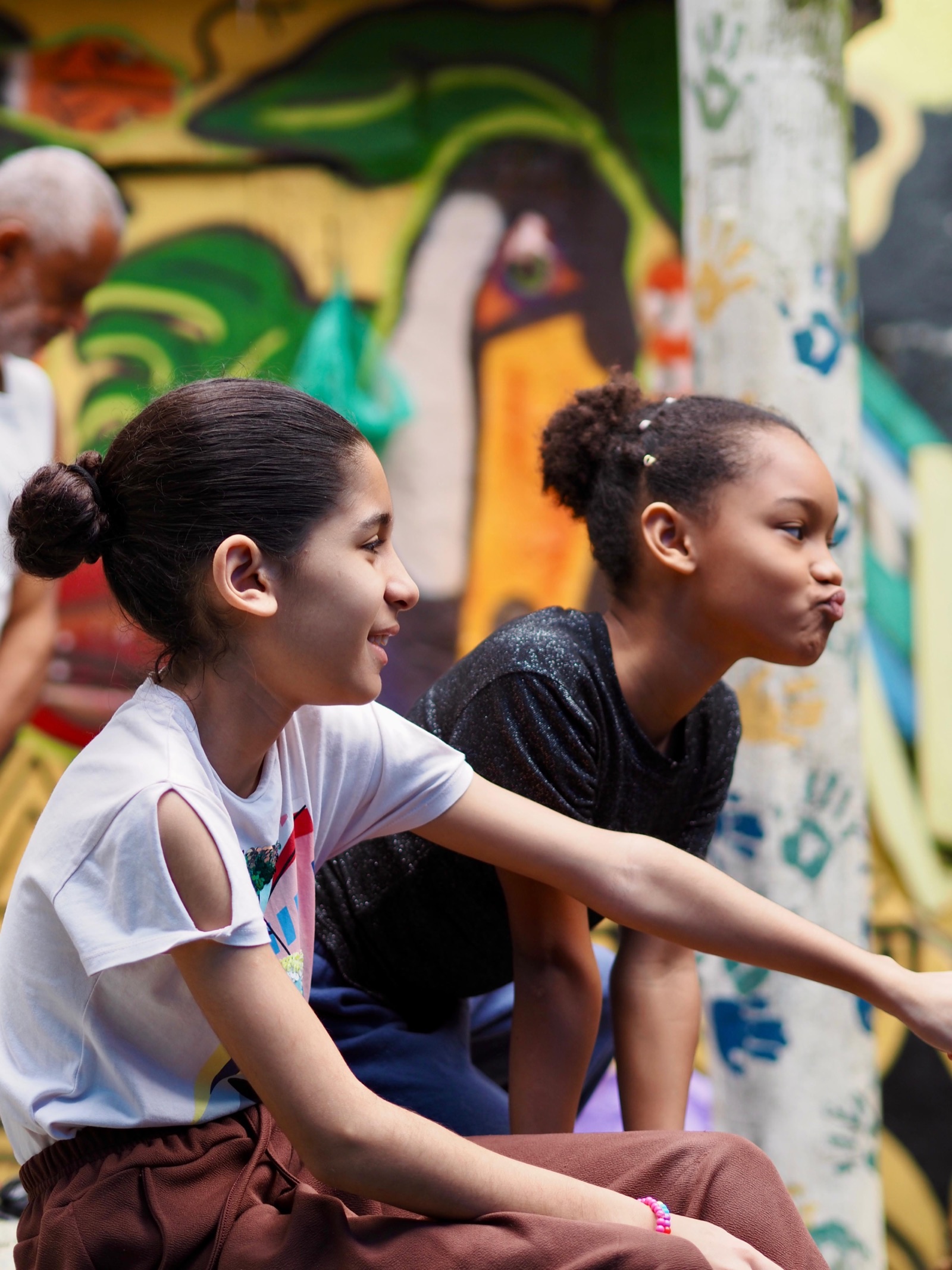 Two girls point at a colourful mural painted on a wall in Vidigal.