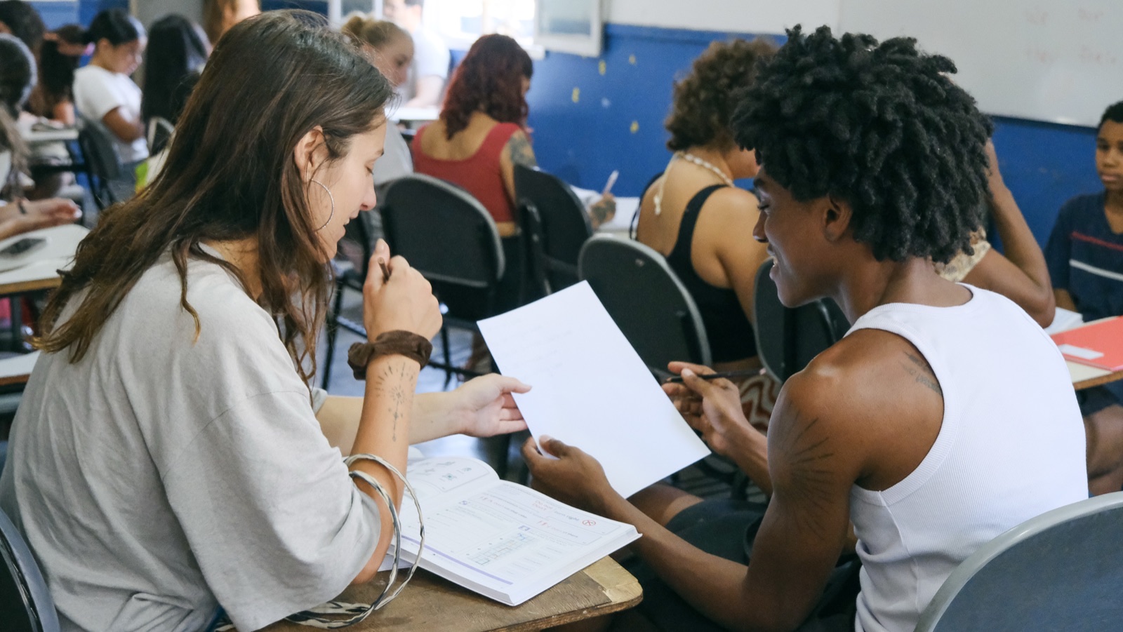 International students go over worksheets with young people in a classroom.