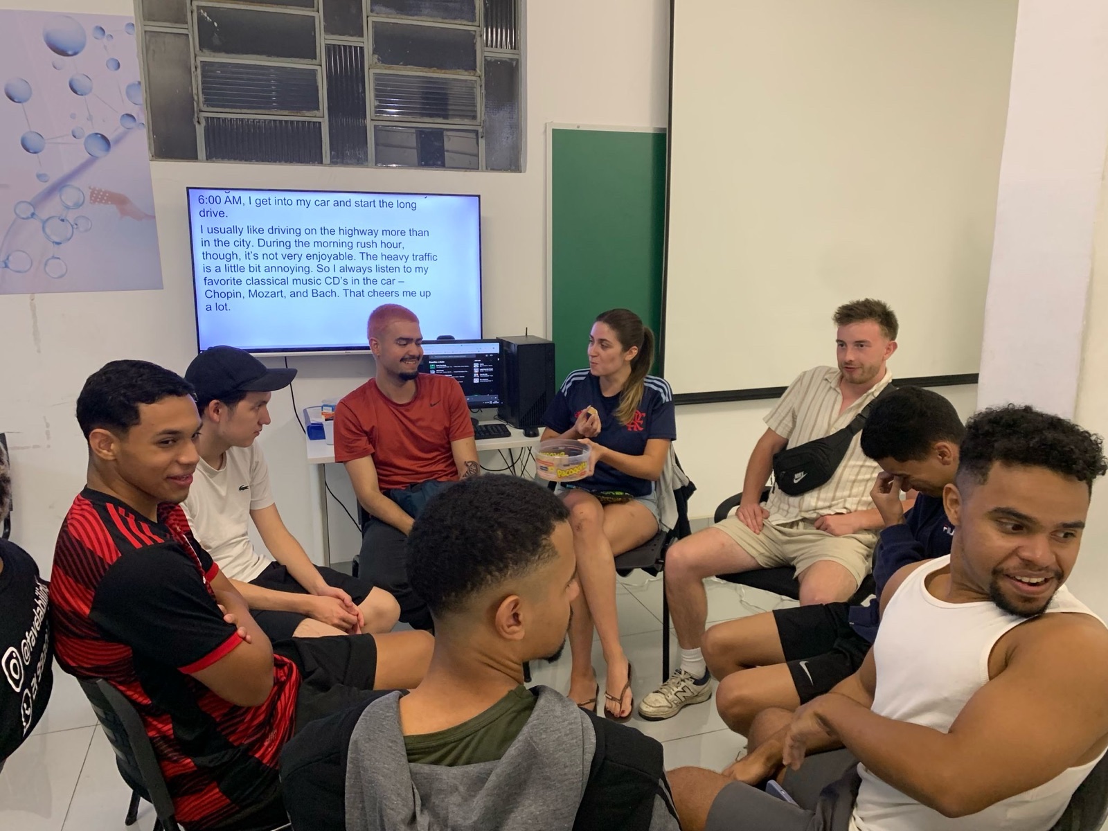 Volunteers and team members sit together in a meeting room, looking at a projected screen.